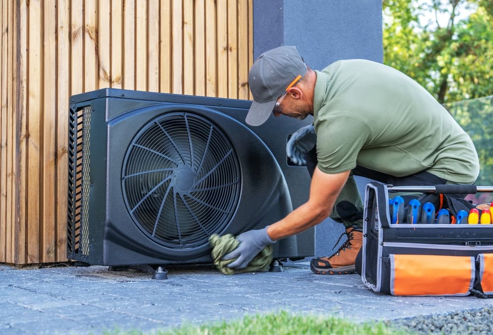 Technician servicing an outdoor HVAC condenser